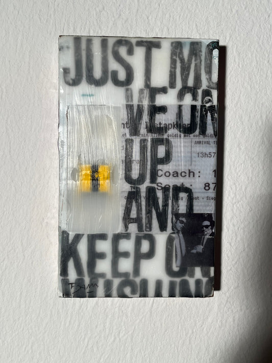 Glass block with text 'JUST KEEP YOUR EYES UP AND KEEP MOVING' on a textured white background